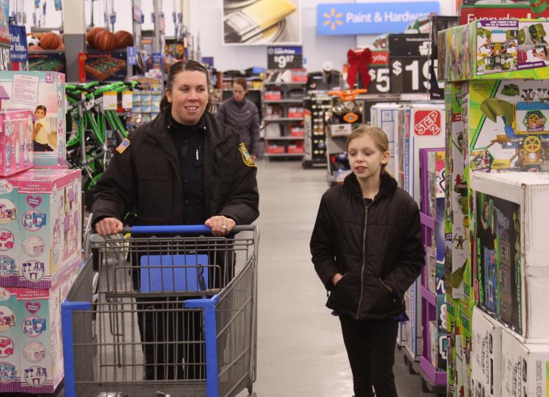 Officer Ashley O'Brien accompanies a young girl during "Shop With a Cop" on Wednesday evening. BY MATTHEW BERNAT